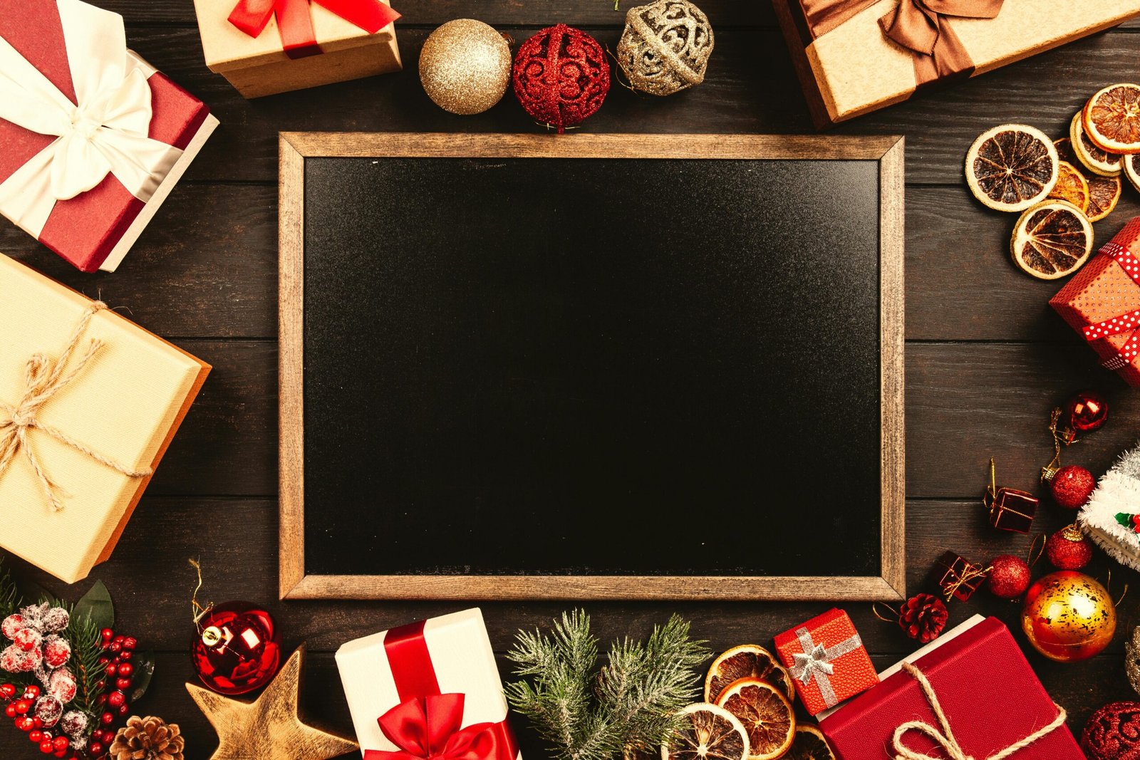 Top-down view of a blackboard surrounded by Christmas gifts and decorations with space for text.